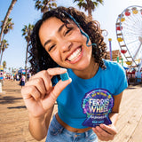 Person smiling and holding a blue gummy and Ferris Wheel Blue Razz pouch on a boardwalk with a Ferris wheel behind them.
