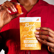 Road Trip Microdosed Mushroom Gummies — a person holding an orange gummy pouch.