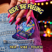 Hand with pink nails tucking a Ferris Wheel Pink Stardust two-tablet pouch into a denim pocket with party lights behind.