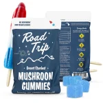 Alt Text: Road Trip Rocket Pop Mushroom Gummies pouch displayed with red, white, and blue rocket pop popsicles and sugar-coated blue mushroom gummies in front.