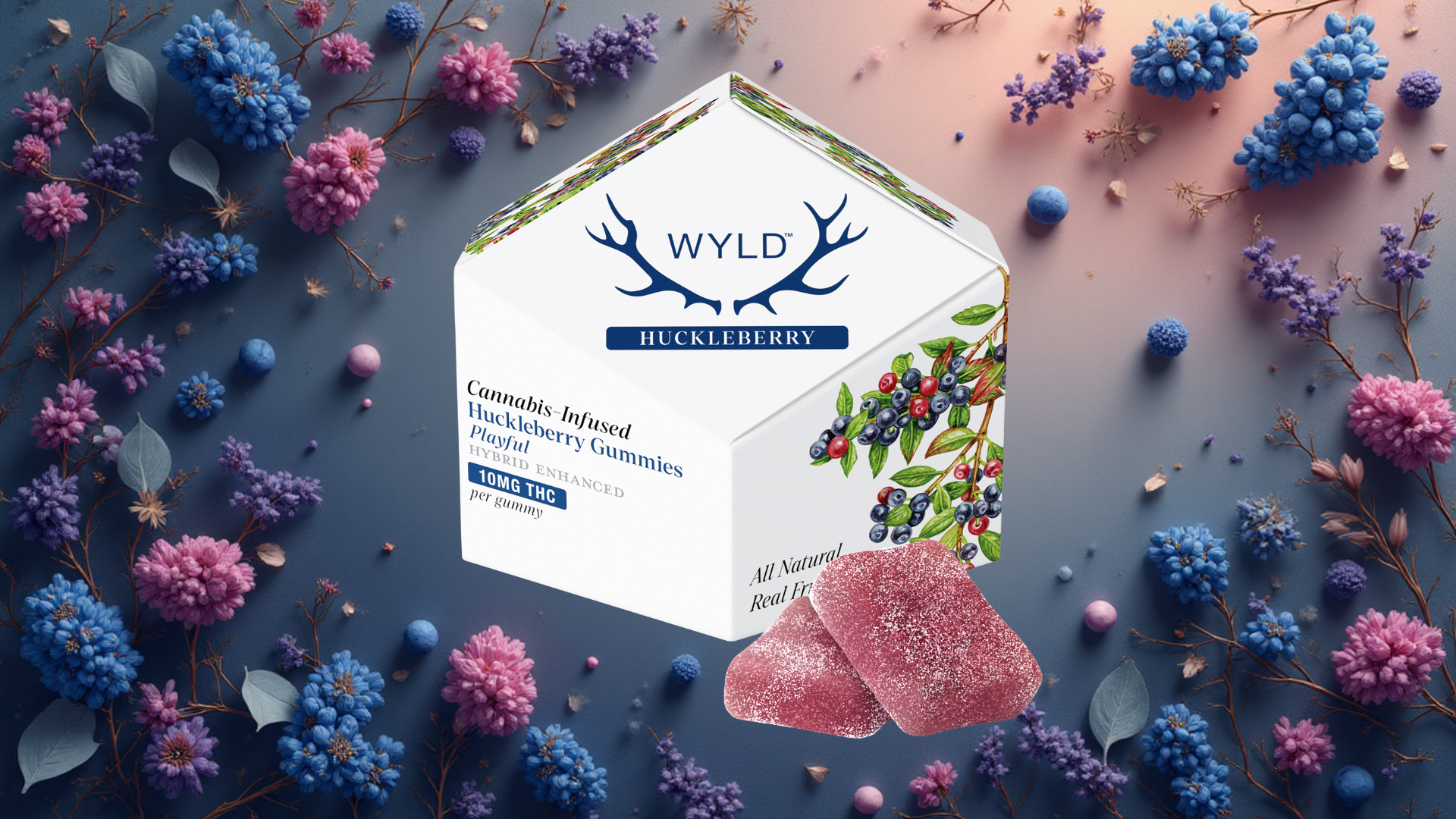 Image of Wyld Huckleberry Cannabis-Infused Gummies packaging surrounded by colorful flowers. The white hexagonal box features the Wyld logo with antlers and text reading “Cannabis-Infused Huckleberry Gummies, Playful Hybrid Enhanced, 10mg THC per gummy.” The packaging includes illustrations of huckleberries and leaves. In front of the box are two sugar-coated, pink-purple gummies. The background is decorated with blue, purple, and pink blossoms on a softly lit gradient surface.