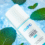 A white bottle of cbdMD Premium Freeze 3000 pain-relieving roll-on gel lies on an icy blue surface surrounded by fresh green mint leaves.
