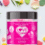 A jar of “Love Bites” female sensual gummies sits centered on a white surface, surrounded by colorful heart-shaped gummy candies, lavender sprigs, rose petals, and green leaves. The jar has a bright pink label with heart patterns and text describing the product’s flavor and features. The gummies inside are pink and sugar-coated.