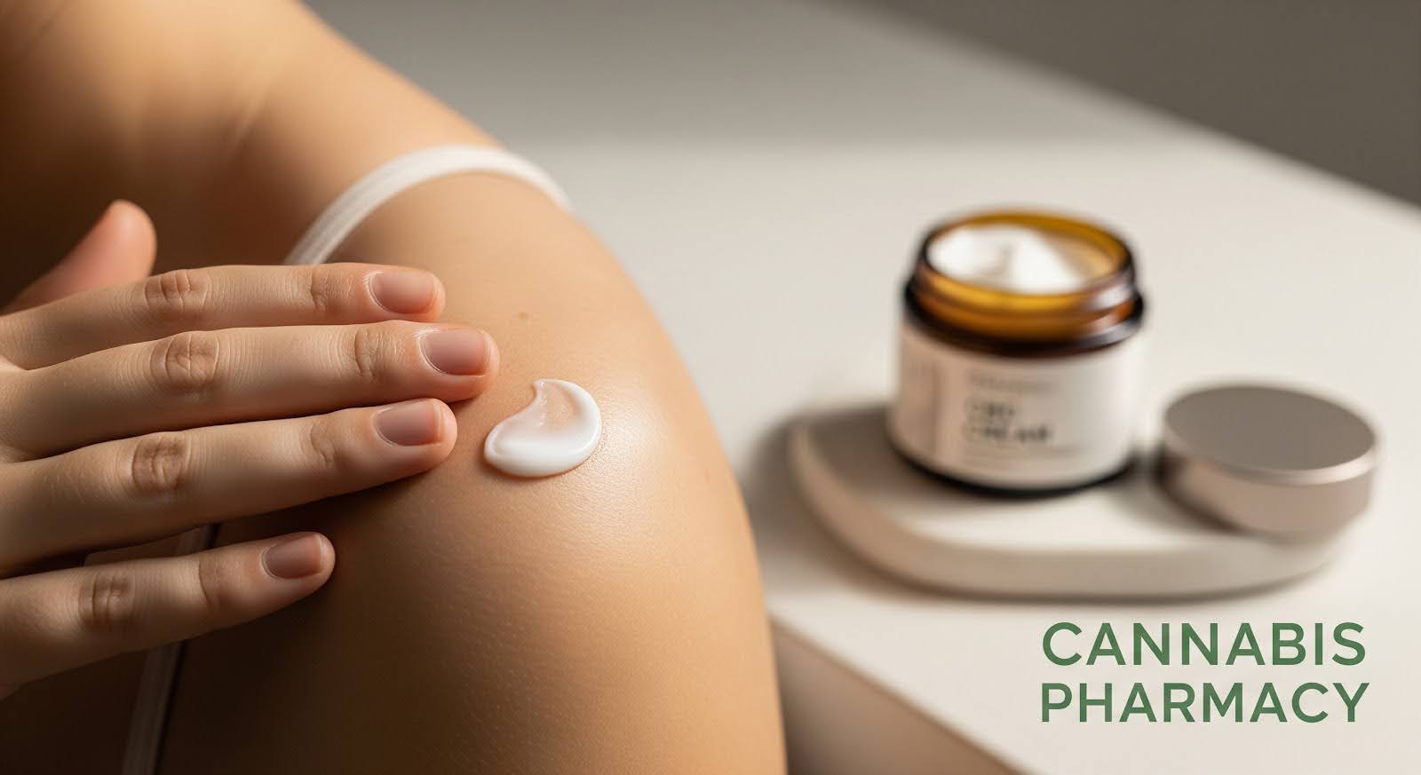 A person applies a dab of white cream to their shoulder, with an open jar of cream in the background on a white surface. The words "Cannabis Pharmacy" appear in green text on the lower right.