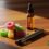 A small pile of colorful sugar-coated gummies sits on a wooden surface beside a brown dropper bottle filled with amber liquid. A sleek vape pen lies in the foreground, and the “Cannabis Pharmacy” logo appears in green text on the right side.